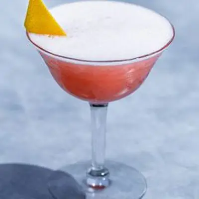 Siesta cocktail served in a coupe glass and garnished with grapefruit peel, shot against marble backdrop