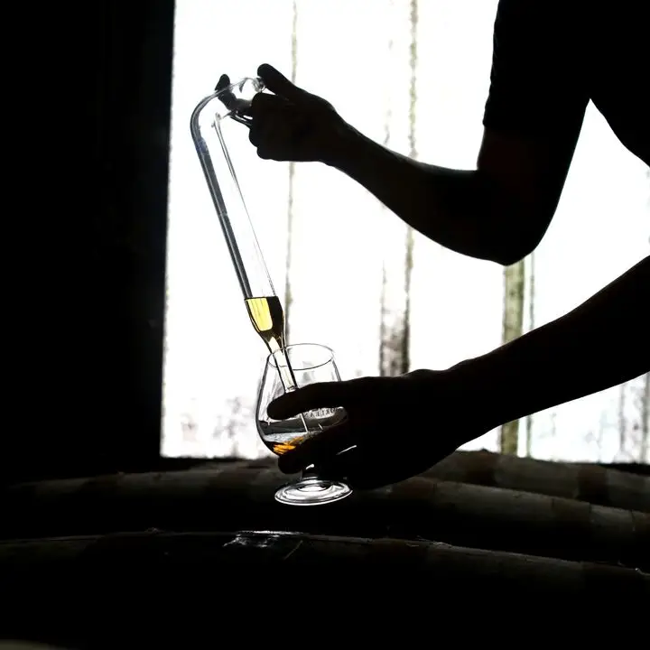 pulling rhum from a barrel at a distillery