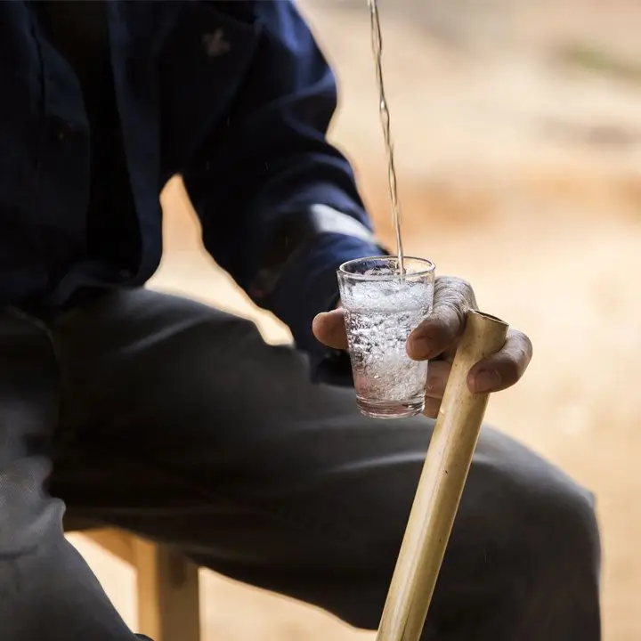 A mezcalero pouring mezcal into a small tasting glass