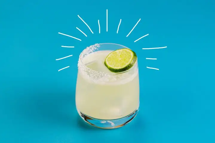 A spicy Margarita served in a clear rocks glass, rimmed with salt and garnished with a lime wheel