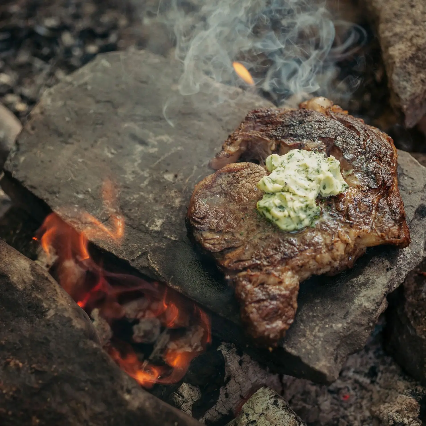 Bife em uma pedra quente com manteiga de ervas selvagens